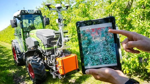 Ein Traktor, ausgestattet mit Technik aus dem Projekt "SAMSON" (Smarte Automatisierungssysteme und -services für den Obstanbau an der Niederelbe) fährt durch die Baumreihen.