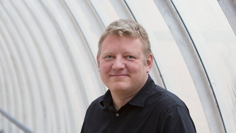 Andreas Herrler steht im Gang eines SWR-Gebäudes. 