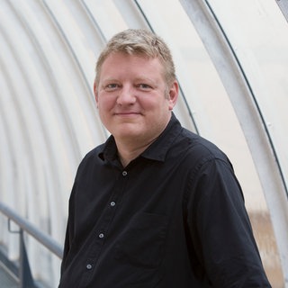 Andreas Herrler steht im Gang eines SWR-Gebäudes. 