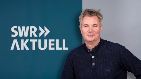 Gerald Pinkenburg steht vor dem Logo von SWR Aktuell.