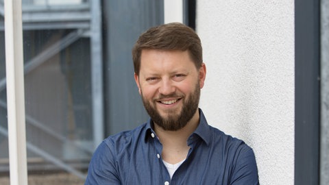 Jonathan Hadem steht im Gang eines SWR-Gebäudes.