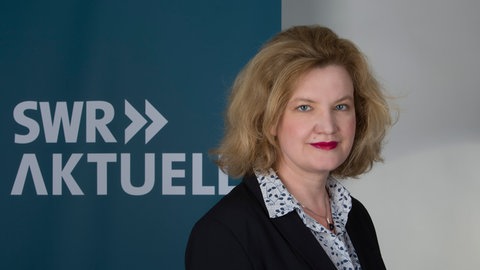 Katja Burck steht vor dem Logo von SWR Aktuell.