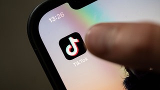 Ein Nutzer ist kurz davor, auf einem iPhone auf das Icon der App Tiktok zu drücken.