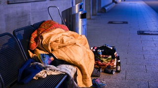 Ein Obdachloser schläft auf einer Bank