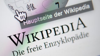 Unter einem Cursor steht auf der Startseite mit dem Logo der Internet-Enzyklopädie  "Hauptseite der Wikipedia".