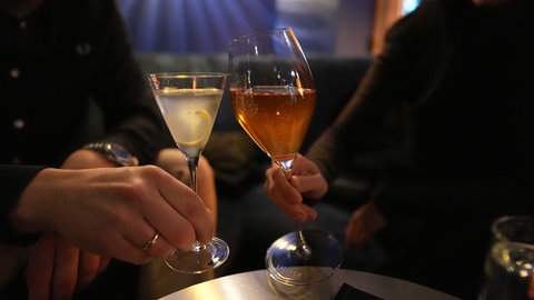 Zwei Menschen stoßen in einer Bar mit Cocktails an