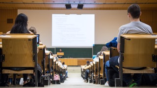 Studentinnen und Studenten sitzen während einer Vorlesung in einem Hörsaal.
