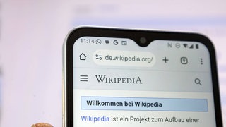 Smartphone mit geöffneter Wikipedia-Seite (Symbolbild)