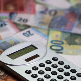 Nach der Landtagswahl in RLP forder Kommunen von Gordon Schnieder mehr Geld. Ein Taschenrechner liegt auf verschiedenen Euro-Banknoten.