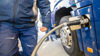 Ein Fahrer betankt an einer Tankstelle sein Fahrzeug.