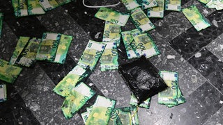100 Euro Scheine liegen auf einem Marmorboden verteilt.
