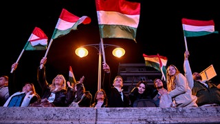 Menschen schwenken Ungarnfahnen.