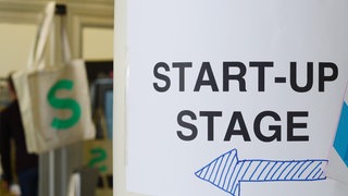 Ein Pfeil zeigt auf einer Konferenz den Weg zur Bühne für Start-ups.