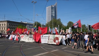 Teilnehmer einer linken Demonstration gehen mit Transparenten und Fahnen eine Straße entlang. Mehrere Tausend Menschen verschiedener Gruppen beteiligten sich an dem Aufzug zum Tag der Arbeit.
