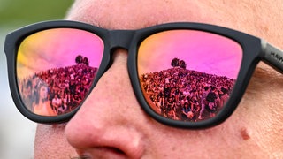 In der Sonnenbrille eines Besuchers beim Open-Air-Festival "Das Fest" in Karlsruhe in der Günther-Klotz-Anlage spiegeln sich Festivalbesucher wider.