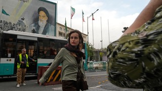 Eine Frau überquert eine Straße vor einem Bild des verstorbenen iranischen Revolutionsgründers Ajatollah Chomeini in der Innenstadt von Teheran