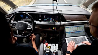 Nijinshan Karunainayagam und Marvin Seegert, wissenschaftliche Mitarbeiter der Technischen Universität München, sitzen im als autonomes Forschungsfahrzeug Edgar eingesetzten Volkswagen VW T7 der Technischen Universität München.