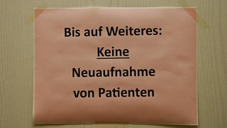 Zettel mit dem Hinweis Bis auf Weiteres: Keine Neuaufnahme von Patienten an der Tür einer Hausarztpraxis