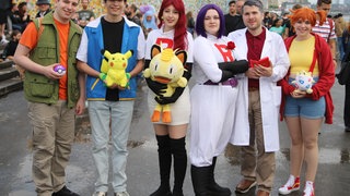 Ein Gruppe verkleideter Teilnehmer aus der Serie Pokemon steht am Rheinufer.