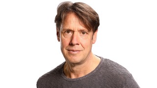 Auf einem Portrait-Foto von Christoph Quarch lächelt der Philosoph mit braunem Pullover in die Kamera