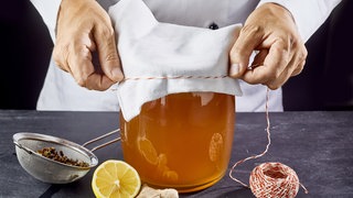 Ein Mann verschließt ein Gefäß mit Kombucha.