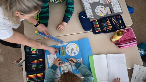 Schüler einer Grundschule arbeiten in einem Klassenzimmer in ihren Heften. 