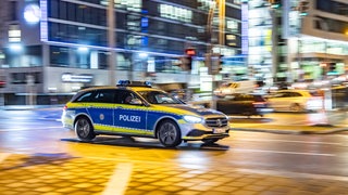 Ein Polizeiauto rast nachts mit Blaulicht durch die Stuttgarter Innenstadt
