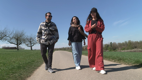 Drei Personen laufen einen Feldweg entlang
