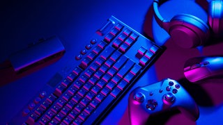 Eine Computertastatur, eine Maus und ein Joystick liegen auf einem schwarzem Hintergrund.