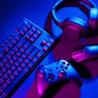 Eine Computertastatur, eine Maus und ein Joystick liegen auf einem schwarzem Hintergrund.