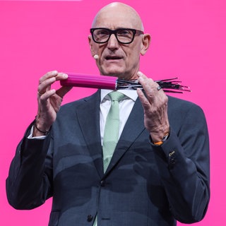 Timotheus Höttges, Vorstandsvorsitzender der Deutschen Telekom, spricht zu den Aktionären mit einem Glasfaser-Kabel in in der Hand. 