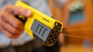Ein Polizist der Bundespolizei führt einen Taser 10 vor. Mit der Pistole werden Pfeile an Drähten verschossen, über deren elektrische Impulse Angreifer "stillgelegt" werden können. 