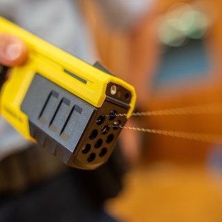 Ein Polizist der Bundespolizei führt einen Taser 10 vor. Mit der Pistole werden Pfeile an Drähten verschossen, über deren elektrische Impulse Angreifer "stillgelegt" werden können. 