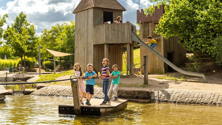 Kinder spielen auf einem Floß auf einem Spielplatz am Rhein.