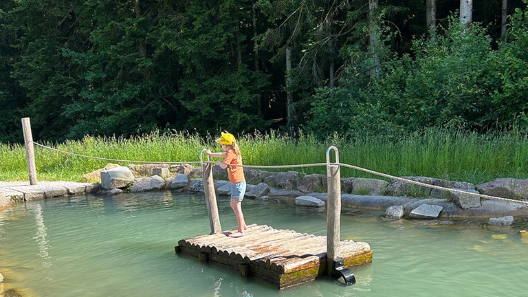 Ein Kind steht auf einem Floß im Zauberland am Kinzigsee.