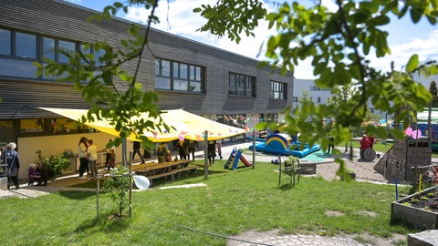 Blick auf das Freigelände einer Kindertagesstätte mit Sonnensegel.