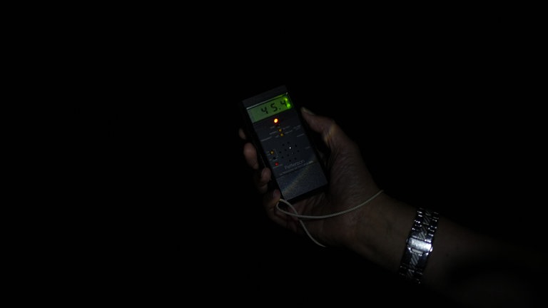 Ein Mann hält ein kleines Gerät mit Display in der Hand.