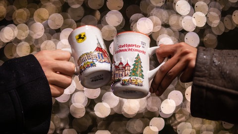 Zwei Menschen stoßen mit Stuttgarter Glühweintassen an