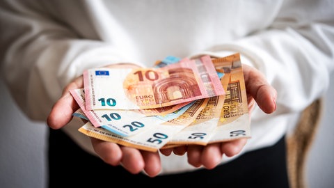 Geldscheine liegen in zwei Händen: In Zeiten großer Krisen spenden Menschen in Deutschland mehr Geld als gewöhnlich.