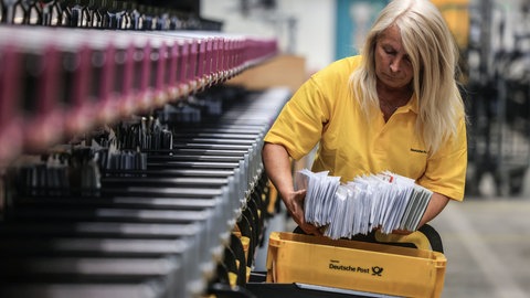 Eine Mitarbeiterin der Deutschen Post sortiert Briefe in einem Briefverteilzentrum. Die Post in Dänemark beendet ihr Briefgeschäft: Ist es auch in Deutschland nur eine Frage der Zeit, bis die Deutsche Post keine Briefe mehr zustellt?