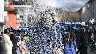 Ein Narr der Mühlbachschreckezunft aus Unzhurst wirft beim Umzug der Bauernfastnacht Konfetti. Egal ob Fastnacht, Fasching oder Fasnet - Narren und Hexen feiern landesweit.