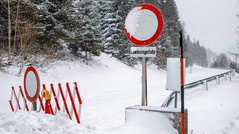 Eine Straßensperre und ein Schild, das auf Lawinengefahr hinweist. Zwei der durch Lawinen umgekommenen Menschen stammen aus Baden-Württemberg, wie Polizeisprecher der Deutschen Presse-Agentur mitteilten.