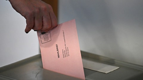 Frau gibt Briefwahlstimme in eine Wahlurne.