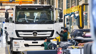 Arbeiter stellen in der Produktionsanlage des Unternehmens Daimler-Truck einen Lastwagen fertig.