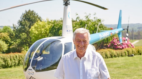 Der Weltenbummler und Stiftungsgründer Reiner Meutsch steht vor seinem Helikopter. 