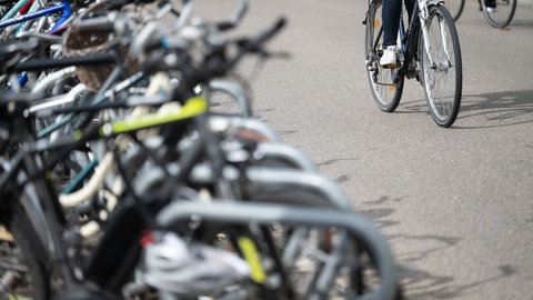 Eine Radfahrerin fährt in der Innenstadt an geparkten Fahrrädern vorbei. 