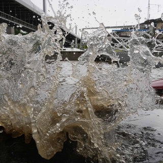 Am Neckar in Stuttgart spritzt das Wasser am Flussufer hoch.