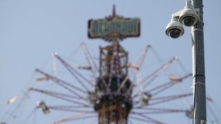 Kameras sind an einem Mast auf dem Festgelände des Stuttgarter Frühlingsfestes zu sehen. 