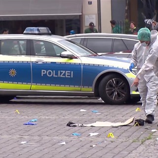 Menschen und ein Polizeiwagen am Tatort