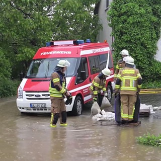 Feuerwehrmänner tragen Sandsäcke in ein Haus